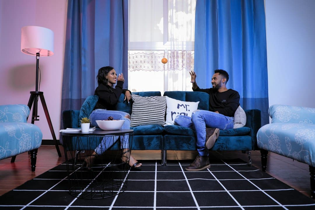 A couple chatting on a blue sofa in a bright living room, ready for a movie night with Moly IPTV